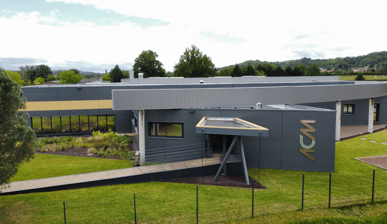 Bâtiment moderne du siège d'ACM France entouré de verdure, avec le logo ACM visible sur la façade.