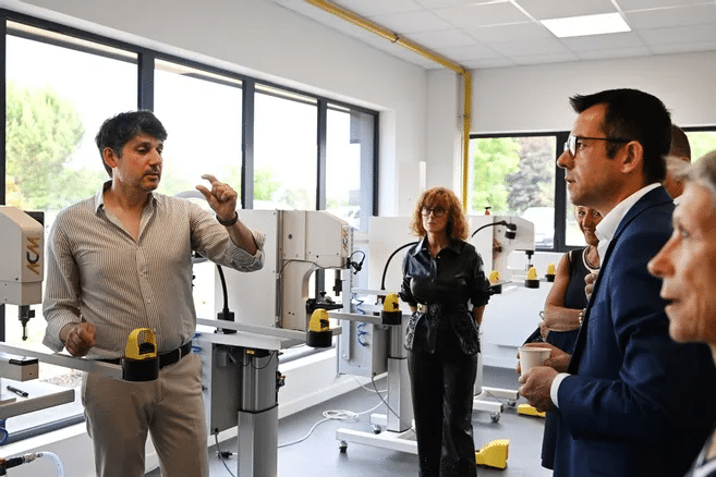 Le PDG en atelier présente le fonctionnement d’une machine industrielle à un groupe de visiteurs, dans un espace lumineux équipé de technologies modernes.