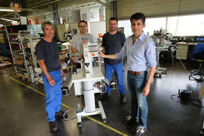 Quatre hommes debout autour d'une machine industrielle dans un atelier.